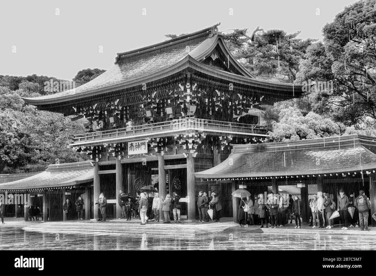 Tokyo, Japan - 31 December 2020: Buiddhist temple complex Meiji-jingu in the middle of green park. Entry gate around inner yard at rain with tourists Stock Photo