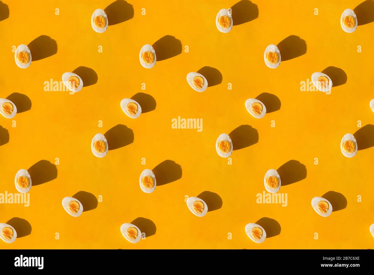 Boiled eggs cut in half on yellow background, flat lay. Stock Photo