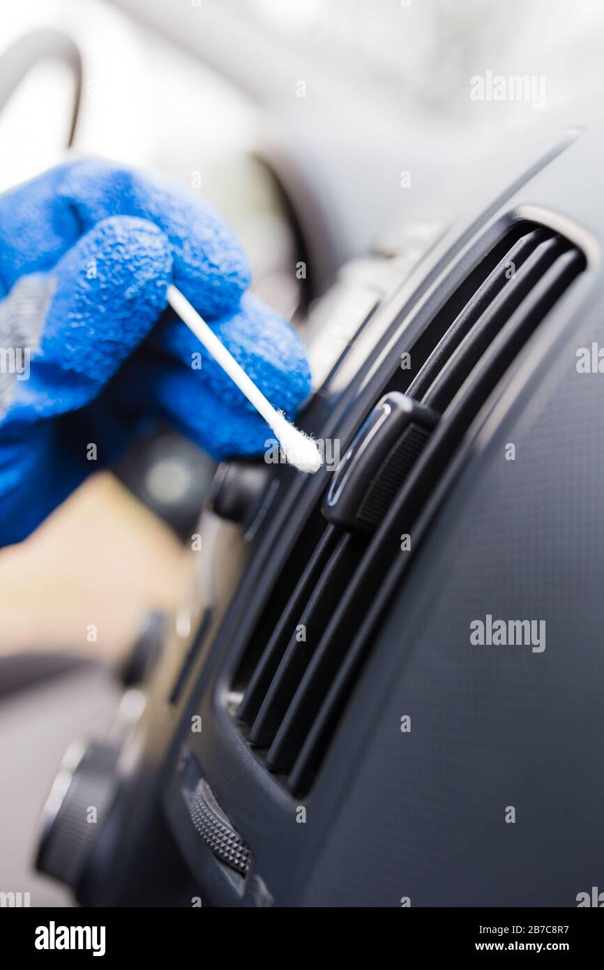 Car service professional holding cotton swab and removing dust from air