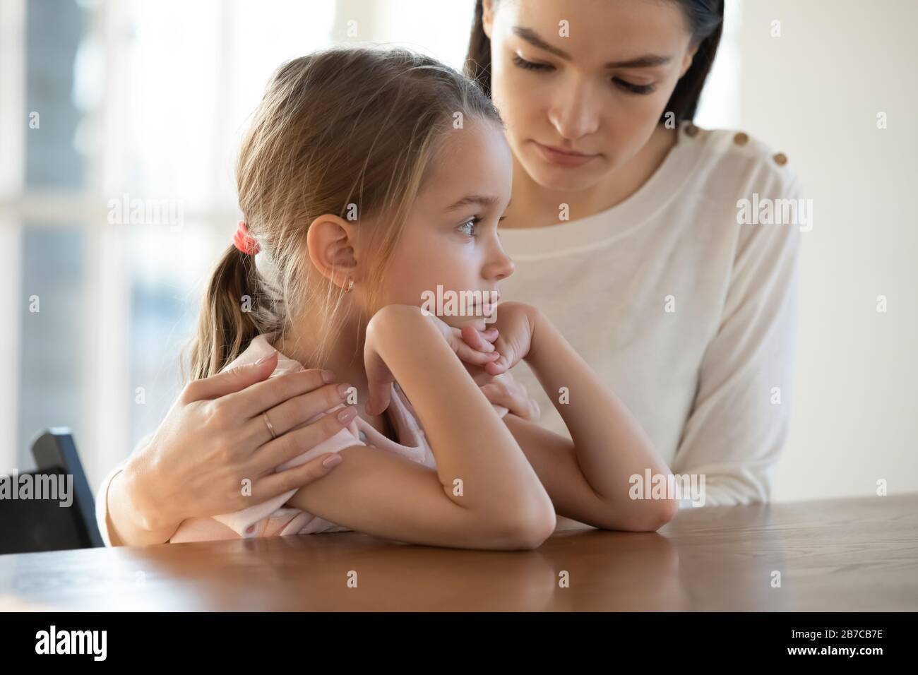 Worried young mother embracing upset little offended daughter. Stock Photo