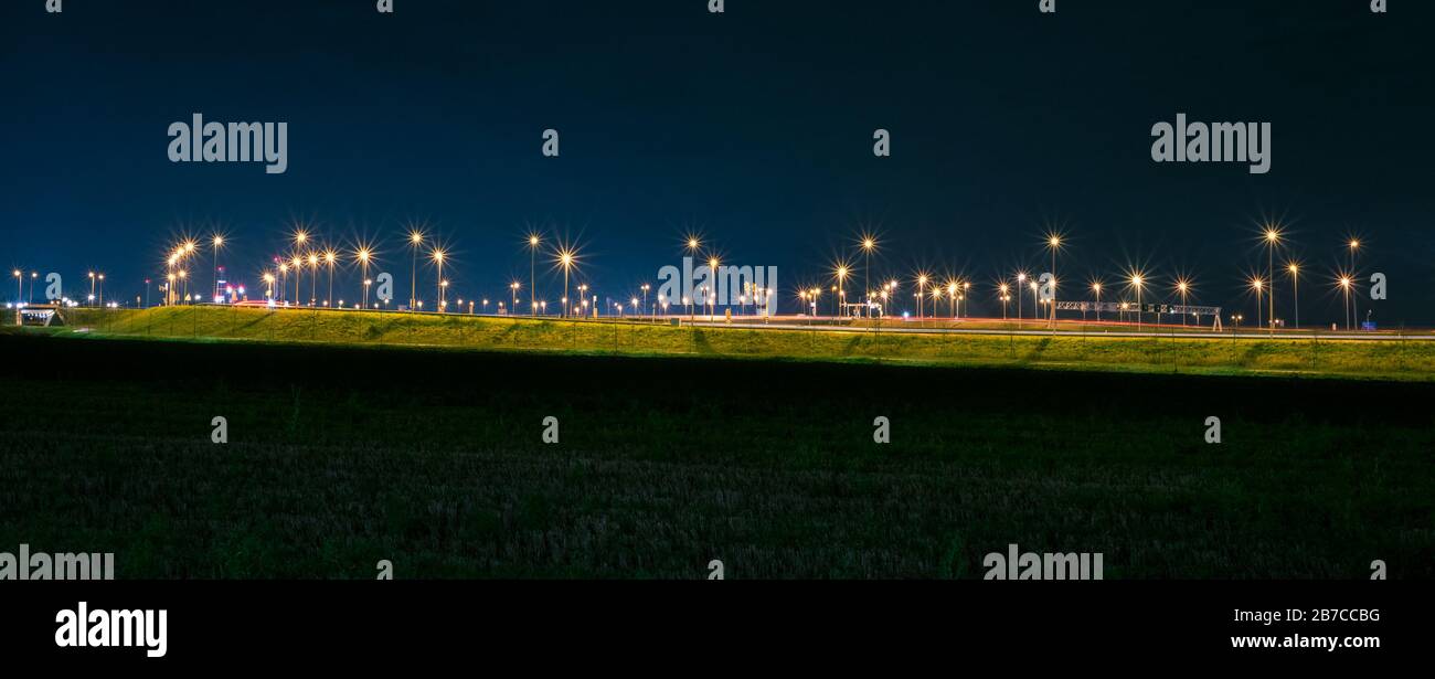 Overpass with many light poles over a highway in The Netherlands at night Stock Photo