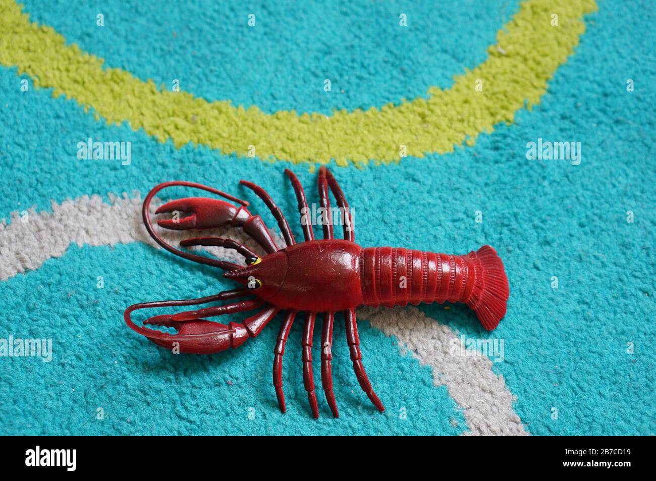 Overhead shot of the red lobster toy on the blue surface Stock Photo