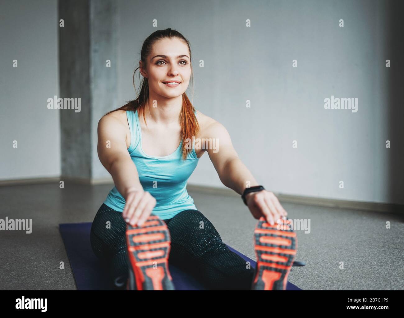 Attractive fit young woman sport wear fitness girl model doing stretching at the loft studio workout class Stock Photo