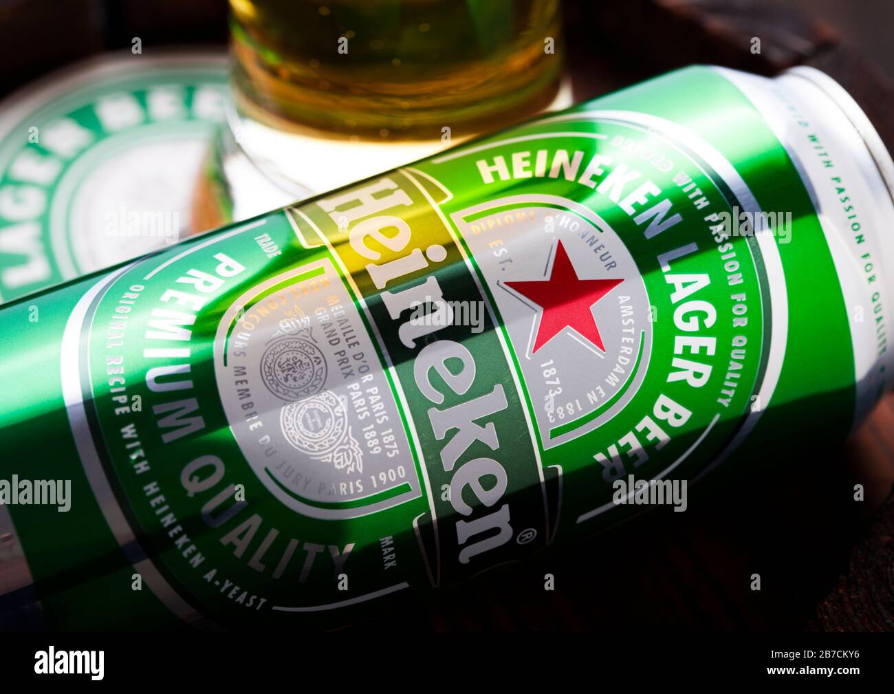LONDON, UK - APRIL 27, 2018: Aluminium can of Heineken Lager Beer on top of old wooden barrel with coaster and glass. Heineken is the flagship product Stock Photo