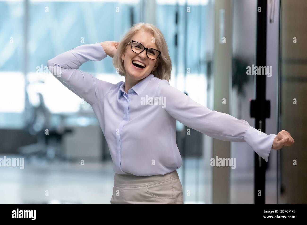 Overjoyed middle-aged businesswoman have fun celebrating work success Stock Photo