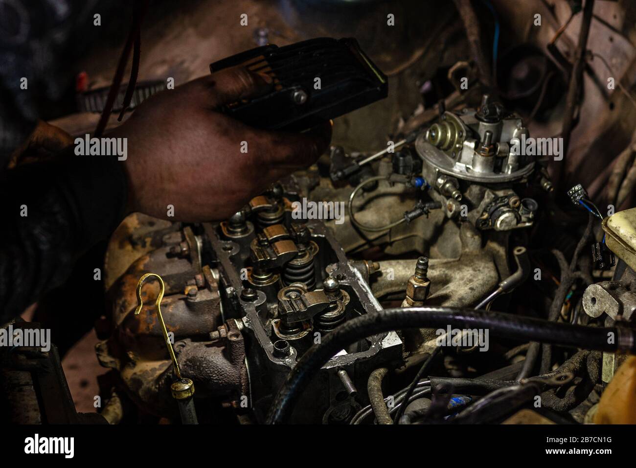 A mechanic shines a flashlight on a defective engine in a car service