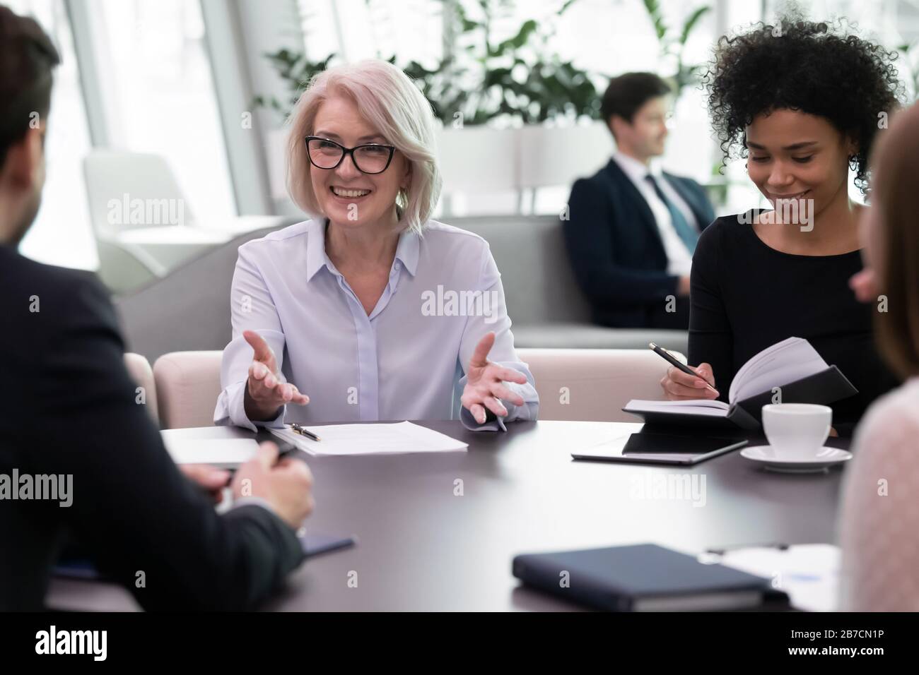 Diverse multiethnic businesspeople discuss paperwork at meeting Stock Photo