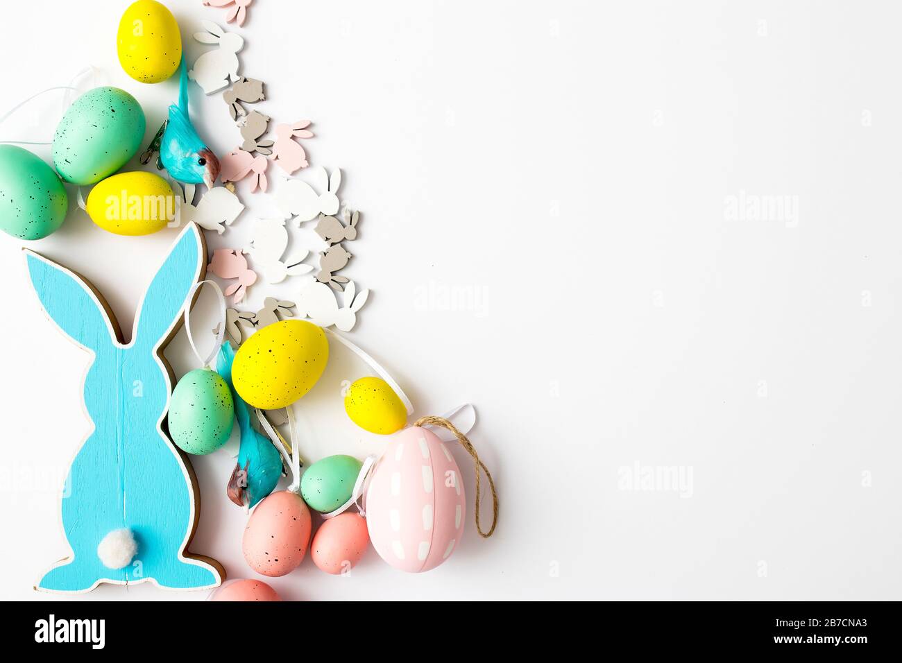 Blue wooden flat easter bunny with plastic eggs lies on a white background. Copy space Stock Photo