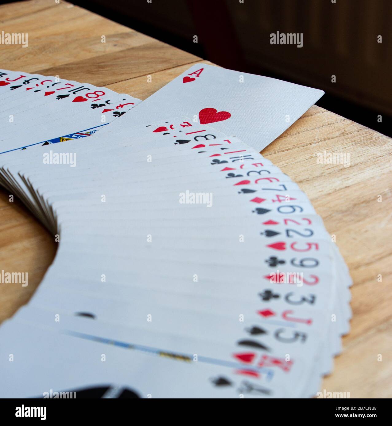 Spread of playing cards with the ace of hearts standing out, wooden surface, depth Stock Photo