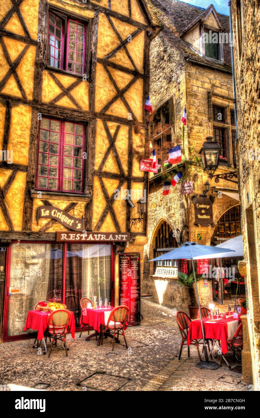 Town of Sarlat-la-Caneda, France. Artistic view of restaurants in Sarlat’s Medieval City streets and lanes, at Rue des Armes. Stock Photo