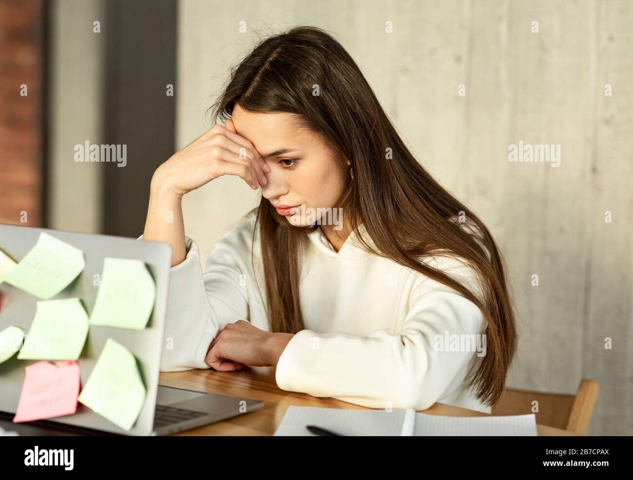 Multitasking freelance Concept. Tired girl holds head Stock Photo