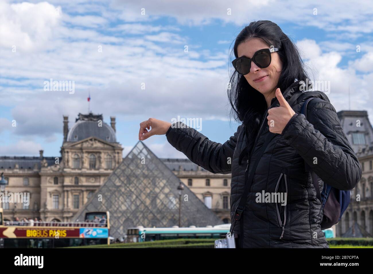 Tourist posing for photograph while pretending to hold the tip of the glass pyramid in front of the Louvre Museum in Paris, France, Europe Stock Photo