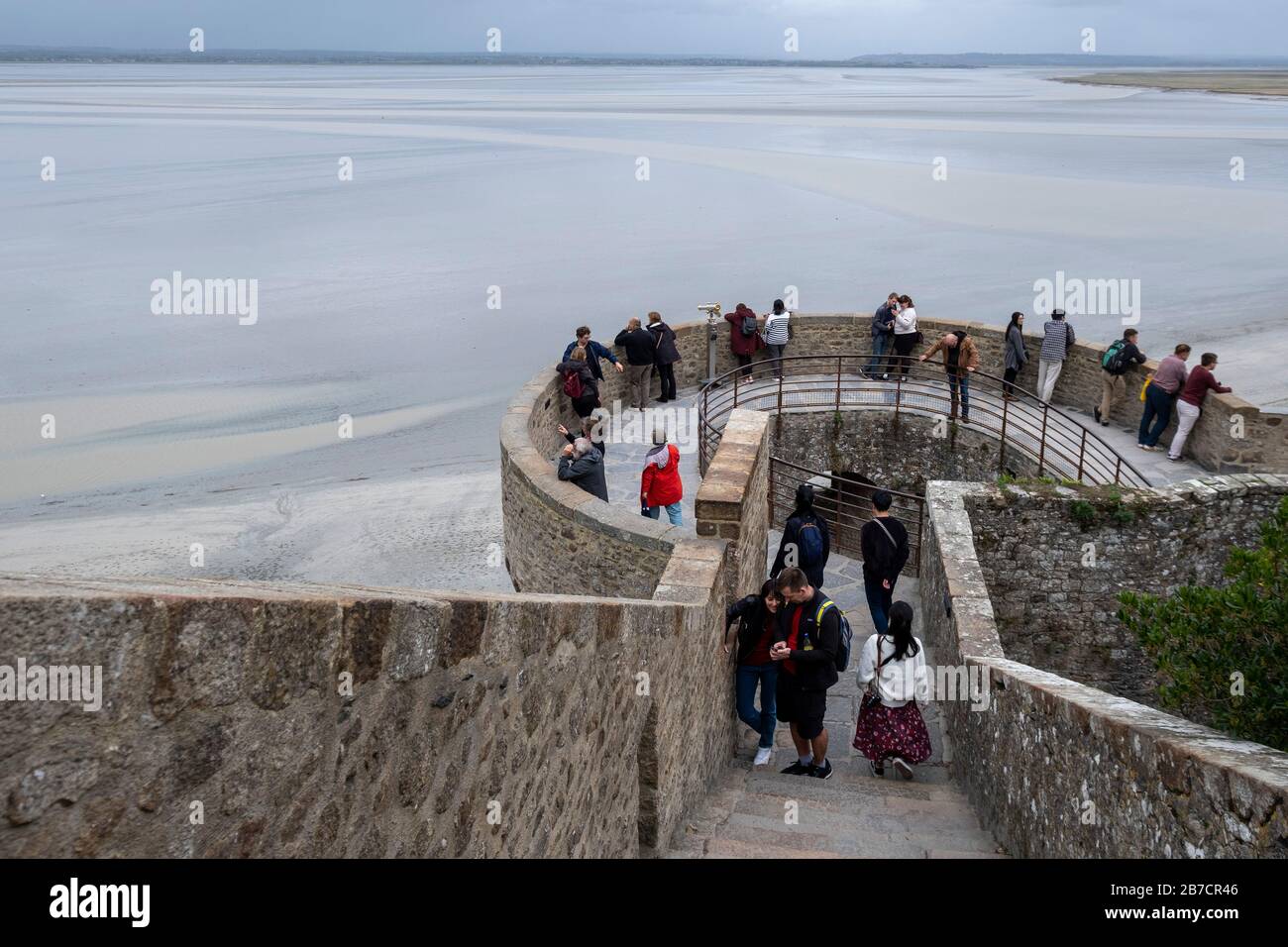 Tourists walking on the city walls overlooking the bay during low tide at Mont Saint-Michel, Normandy, France, Europe Stock Photo