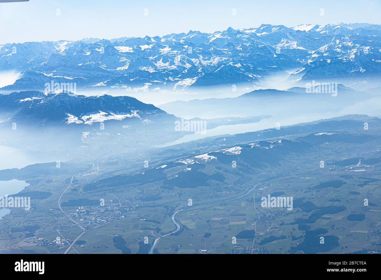 Unique alpine aerial panorama. Blue Planet Earth high altitude aerial view of Swiss Alps lakes, seen from an airplane cabin window flying over Zurich Stock Photo