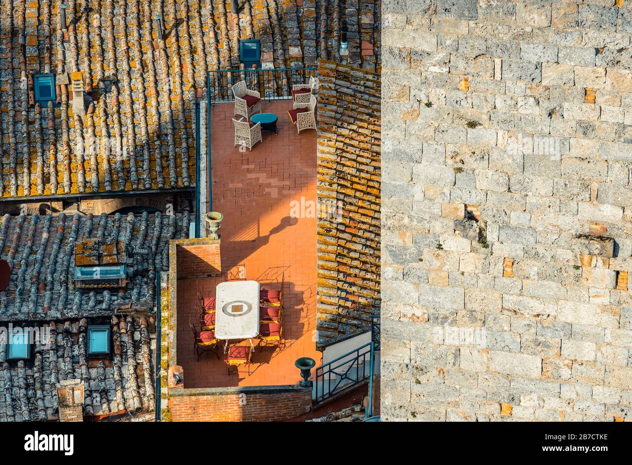 View of a terrace with a dining table and chairs and rooftops in the historic centre of San Gimignano, Tuscany, Italy, from the top of Torre Grossa. Stock Photo