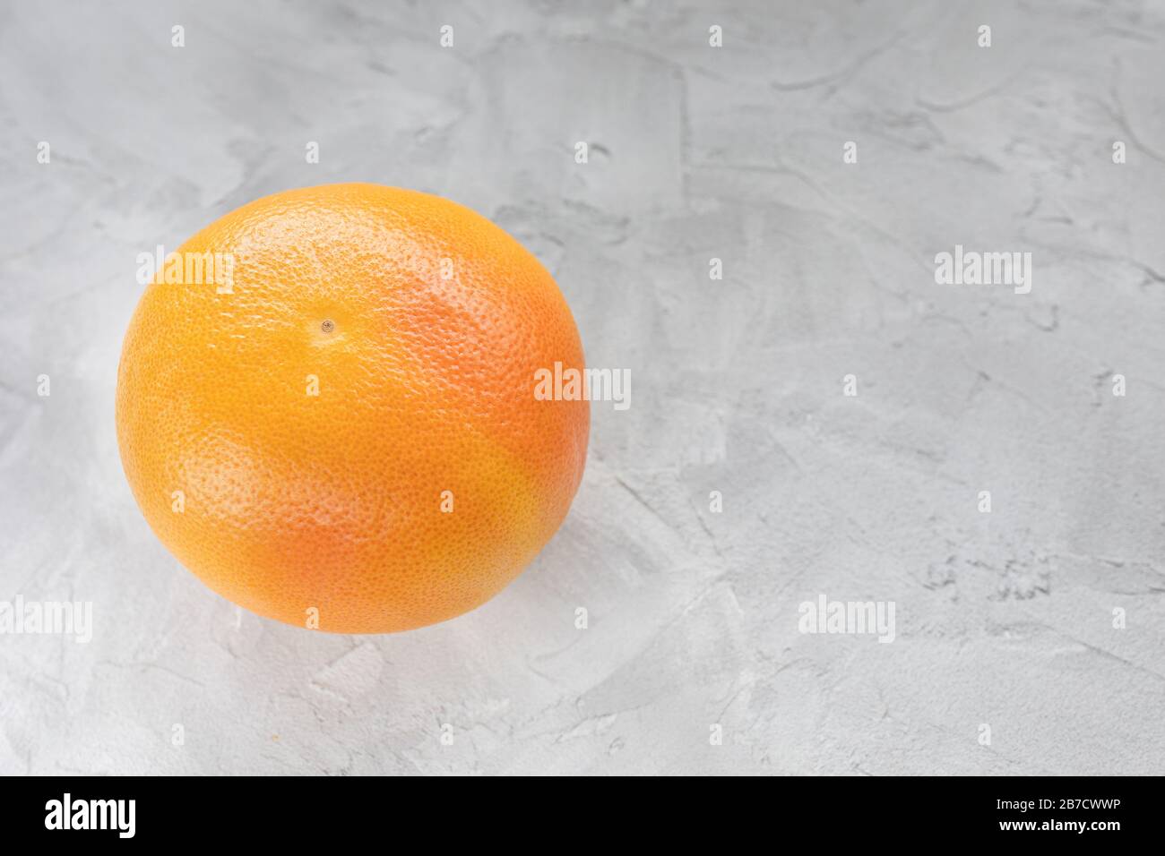 One red ripe grapefruit on gray background. CLose up, copy space Stock Photo