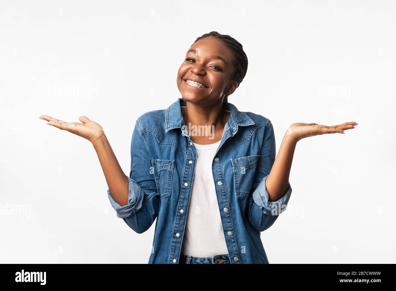 Positive African Girl Shrugging Shoulders Smiling To Camera, Studio Shot Stock Photo