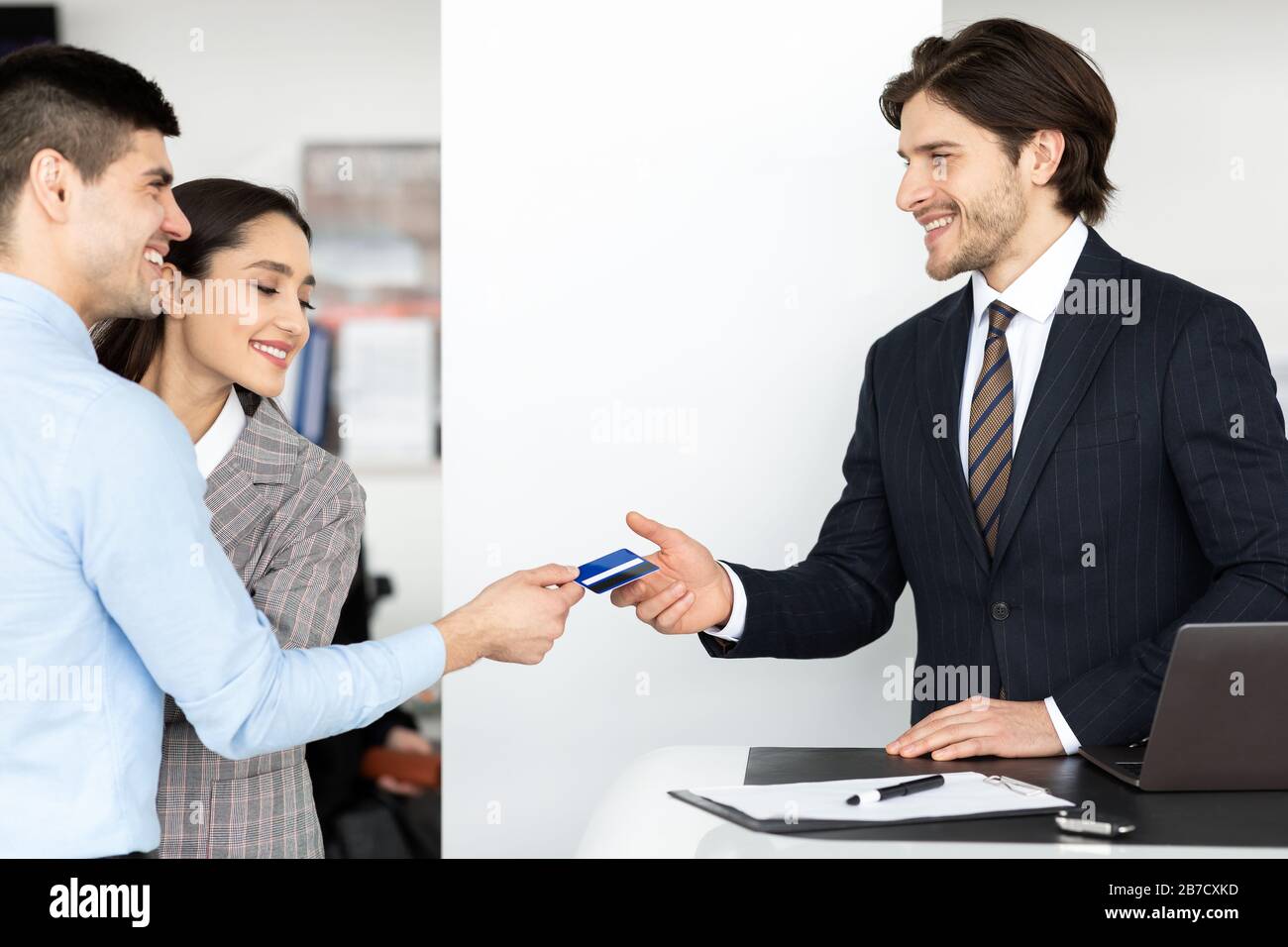 Family Buying Car Giving Seller Credit Card In Dealership Office Stock