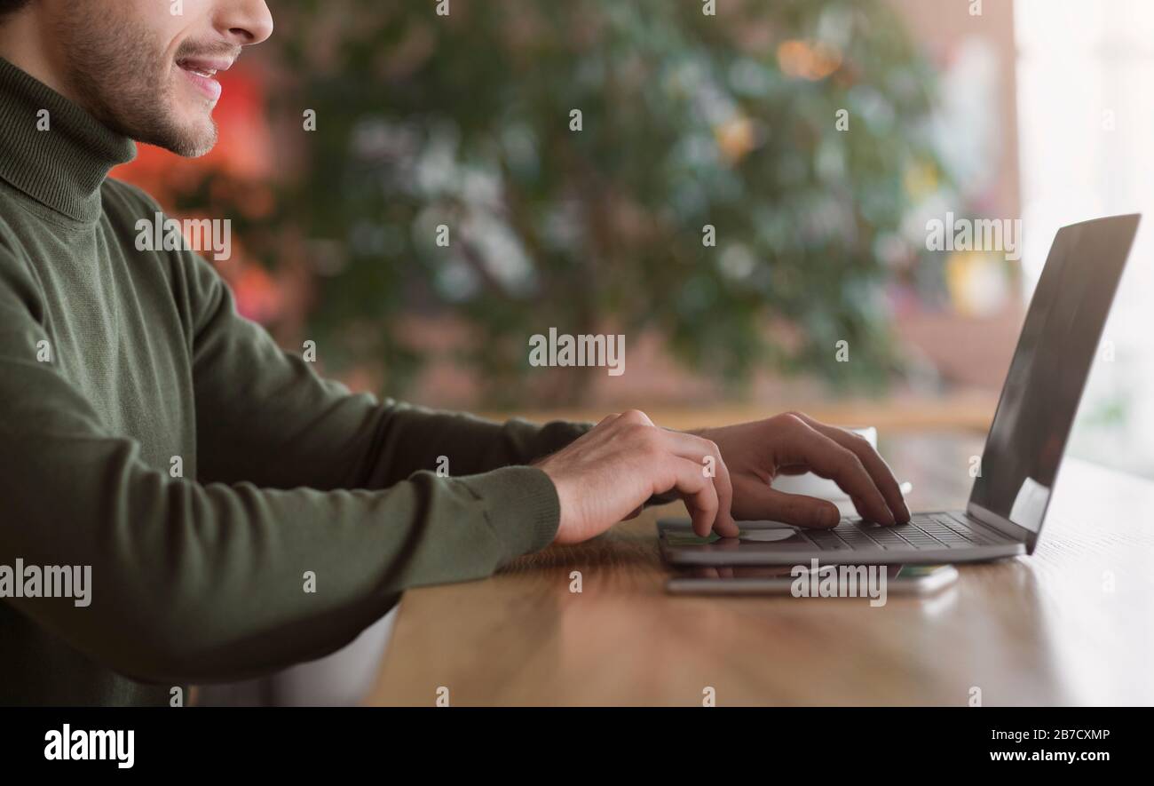 Cropped of male freelancer typing on laptop at cafe Stock Photo