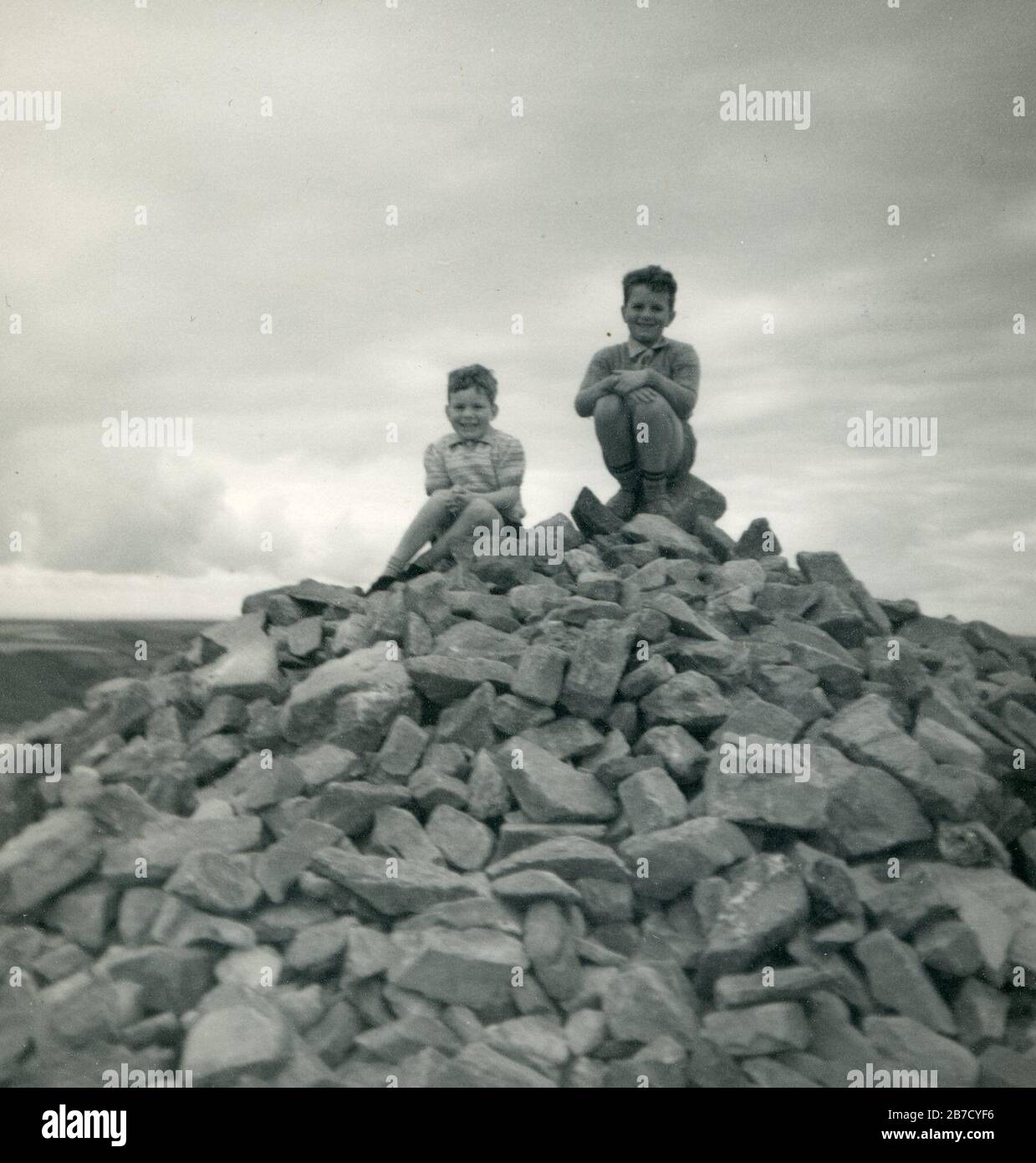 Vintage c.1950s archive snapshot holiday snap of two young boys sat on top of a large pile of rocks. Found photo social history vernacular photograph UK. Photographer unknown (Richard Bradley collection) Stock Photo
