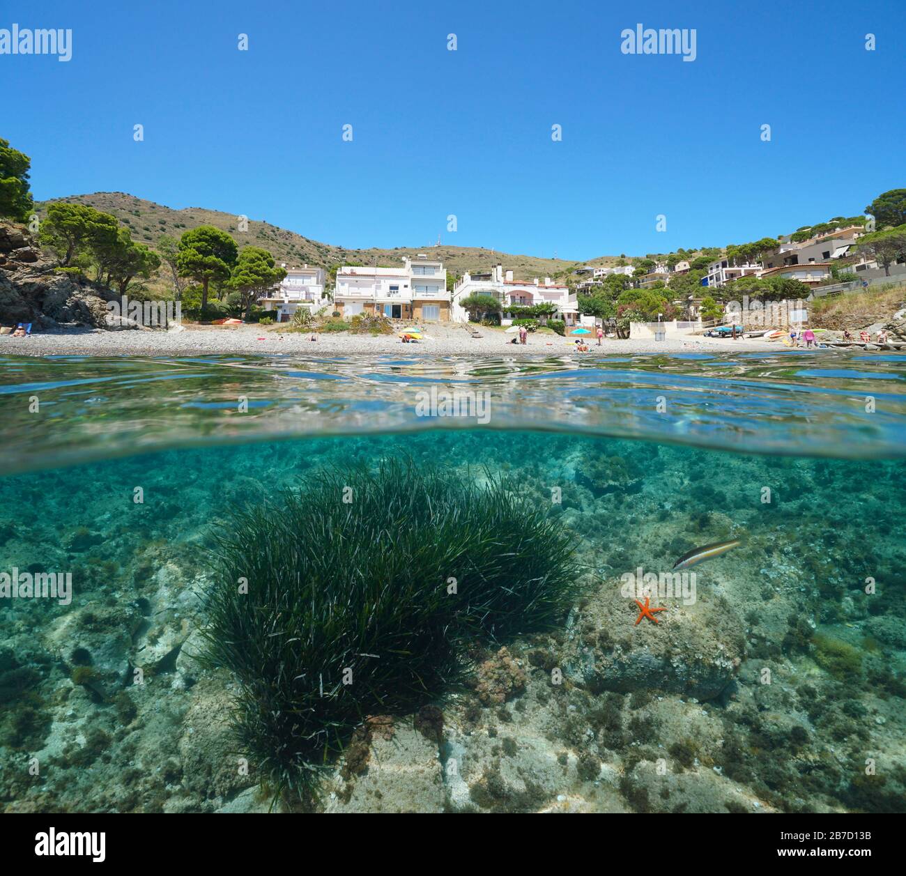 Spain Mediterranean sea summer vacations, beach coastline with buildings, split view over and under water surface, Costa Brava, Colera, Catalonia Stock Photo