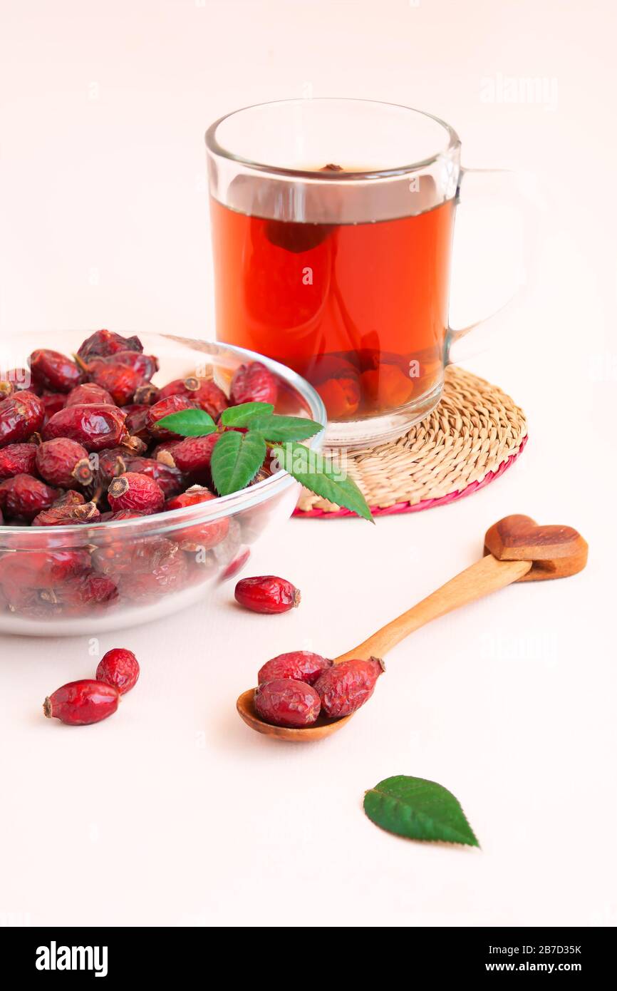 closeup shot of popular flu and cold remedy, dried rosehip berries, in bowl with hot rosehip tea in background Stock Photo