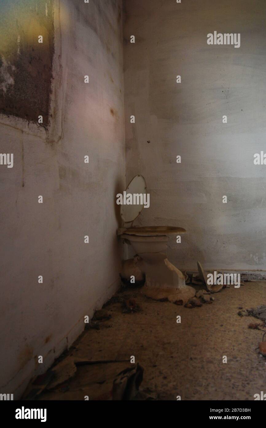 Abandoned and dirty toilet with door to the countryside Stock Photo
