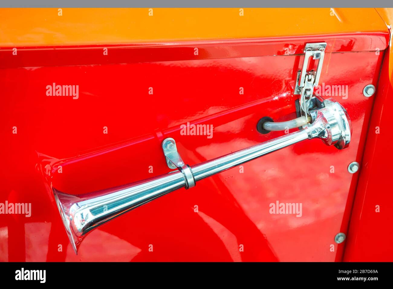 Attention please. Metal horn on red car background. Retro vehicle horn. Car air horn or klaxon