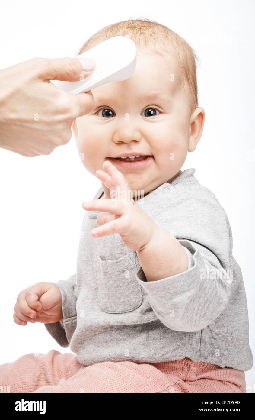 Pediatrician or nurse checks baby boy's body temperature using infrared