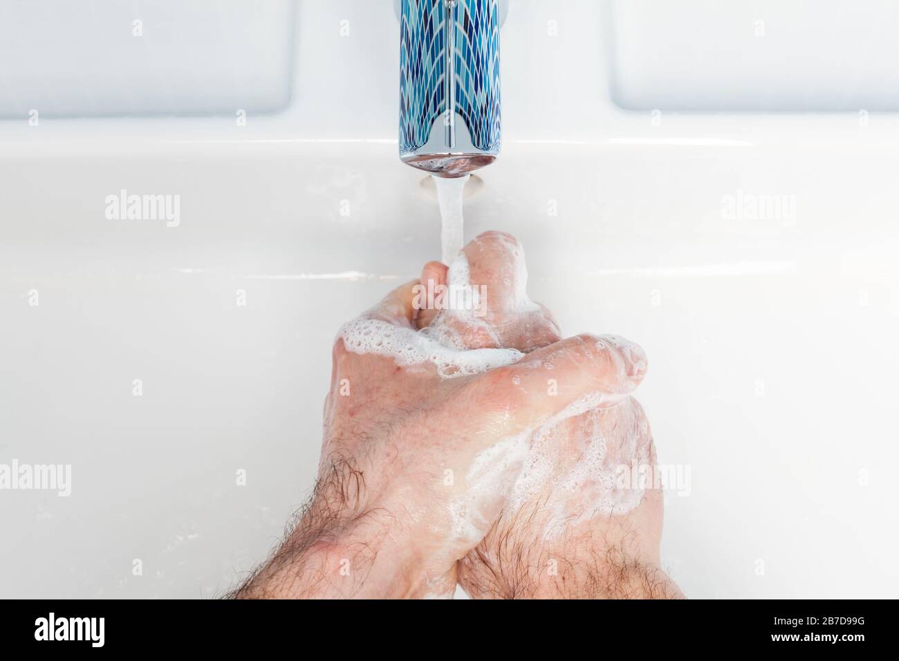Man washing hands with antibacterial soap and water performing basic protective measures against spreading of coronavirus epidemy Stock Photo