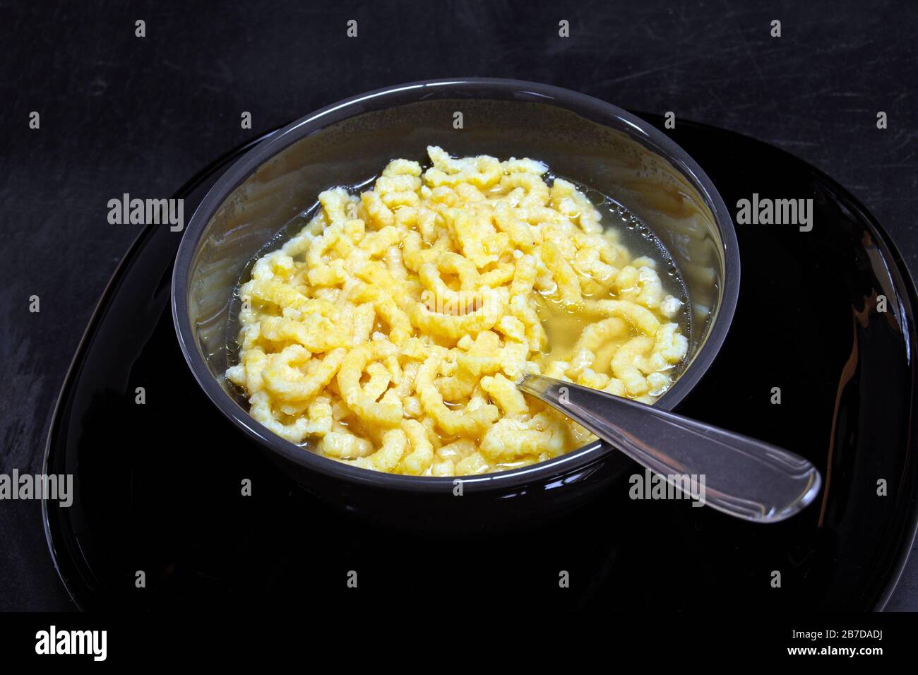 traditional italian pasta in broth passatelli, with black ceramic bowl