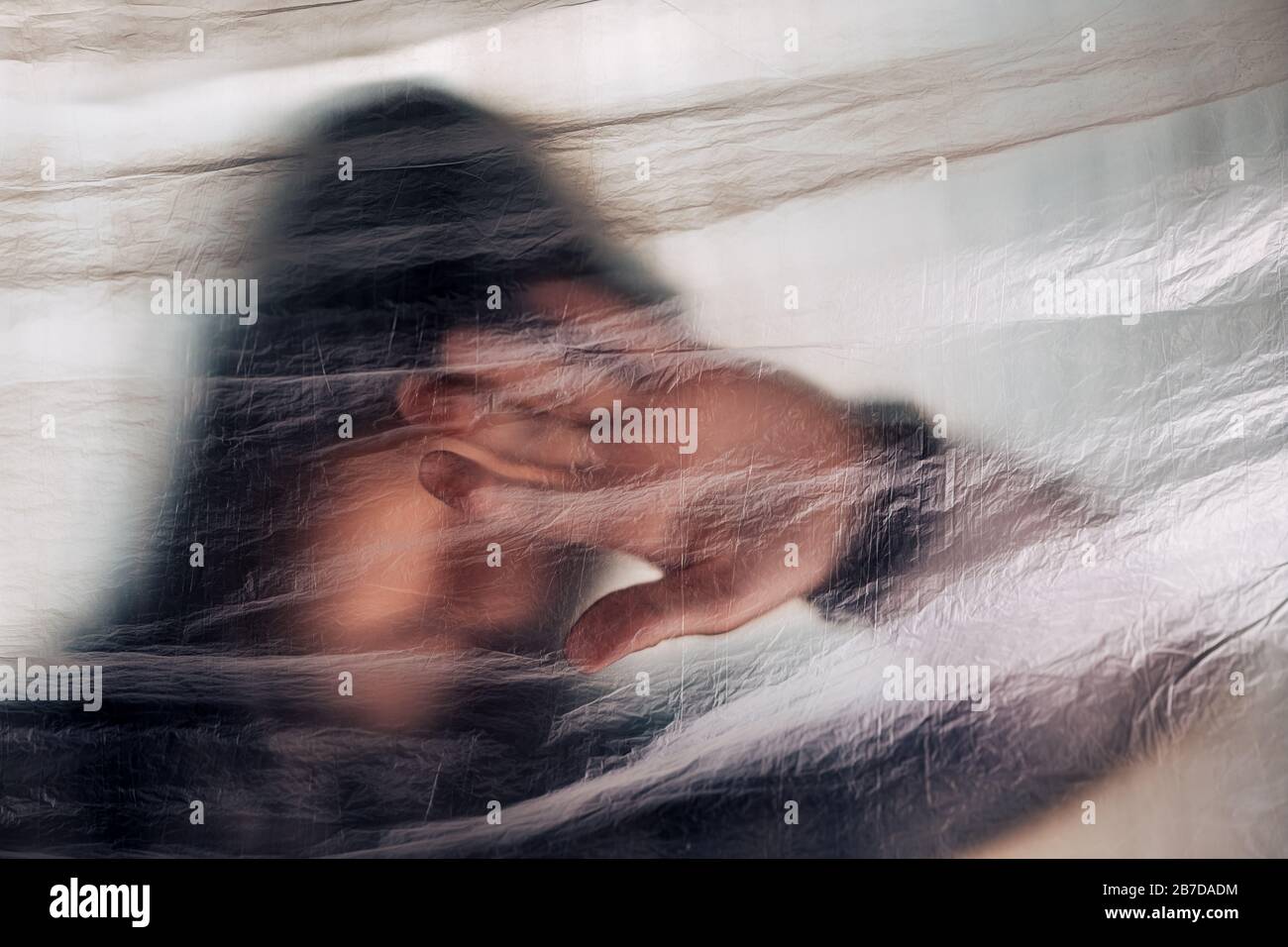 Drug addiction concept, blurred male person with hoodie behind plastic curtain, selective focus Stock Photo