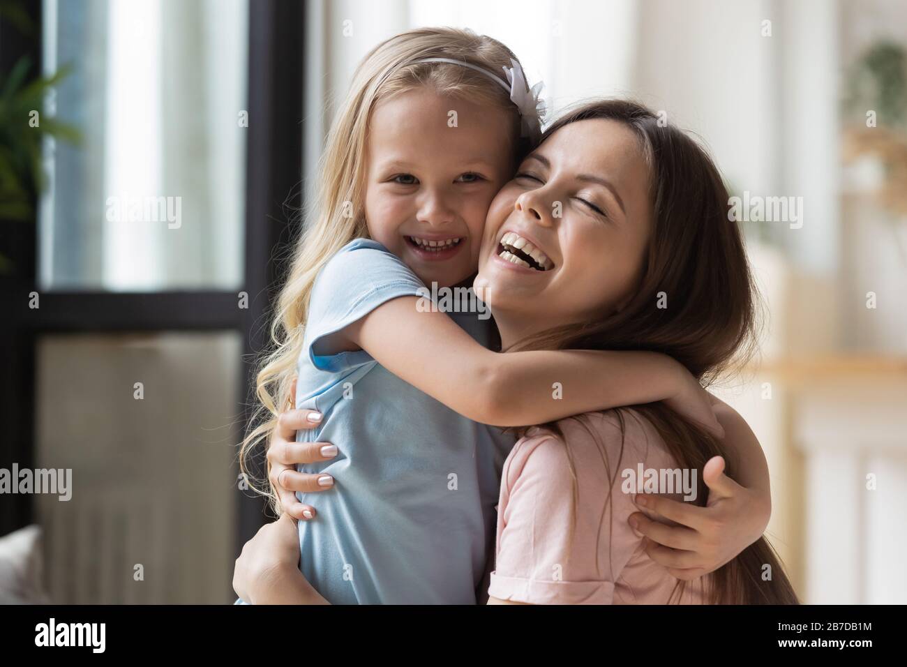 Overjoyed mom and little daughter cuddle showing love Stock Photo