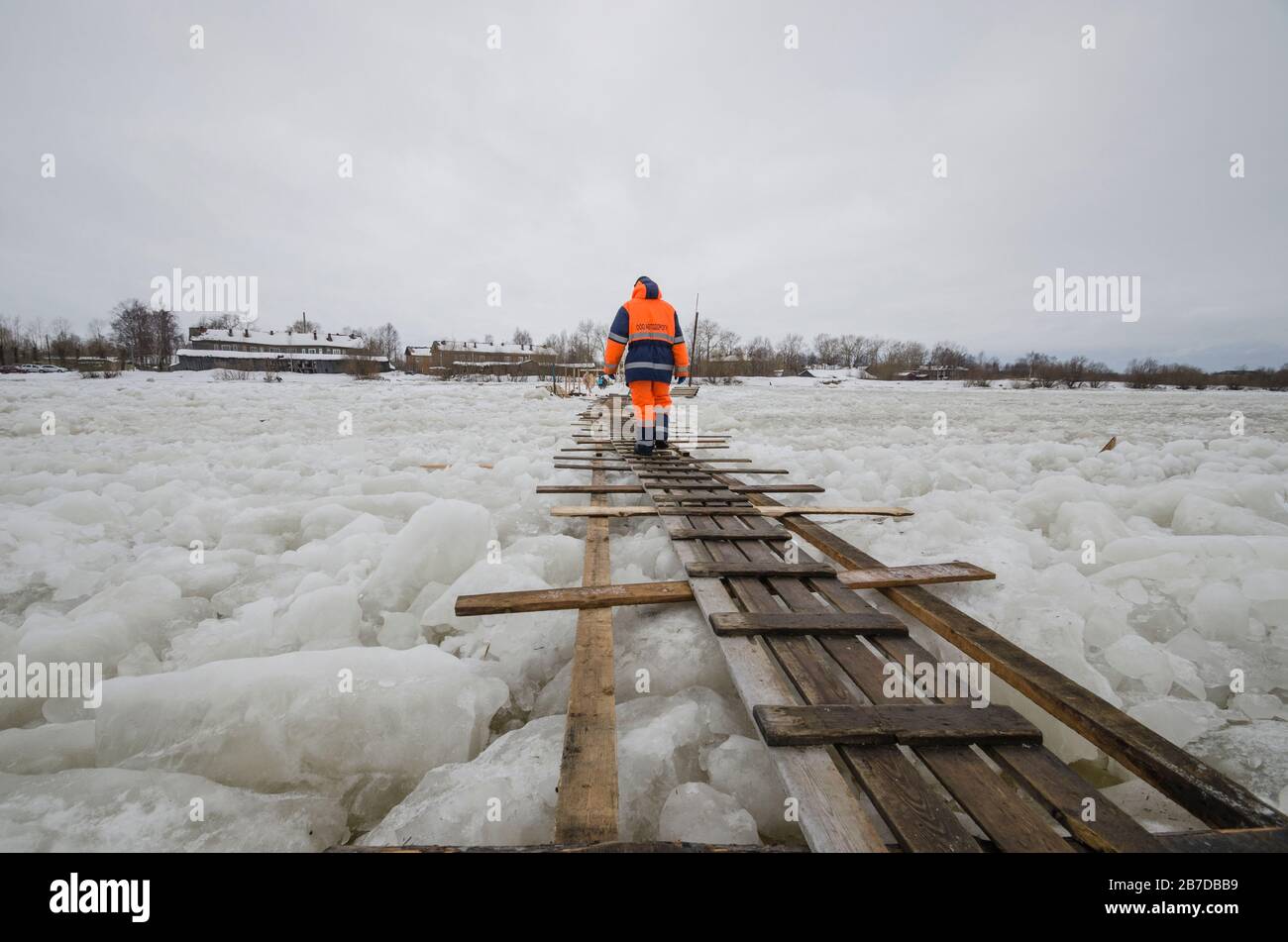 A man walks on the boards through an ice crossing. Crossing a frozen river. Russia, Arkhangelsk Stock Photo