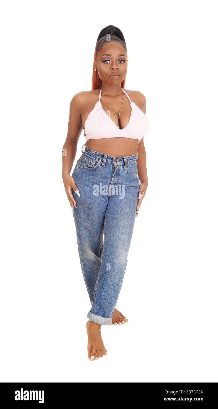 A gorgeous African American woman standing in jeans and a pink bra in the studio looking, isolated for white background Stock Photo