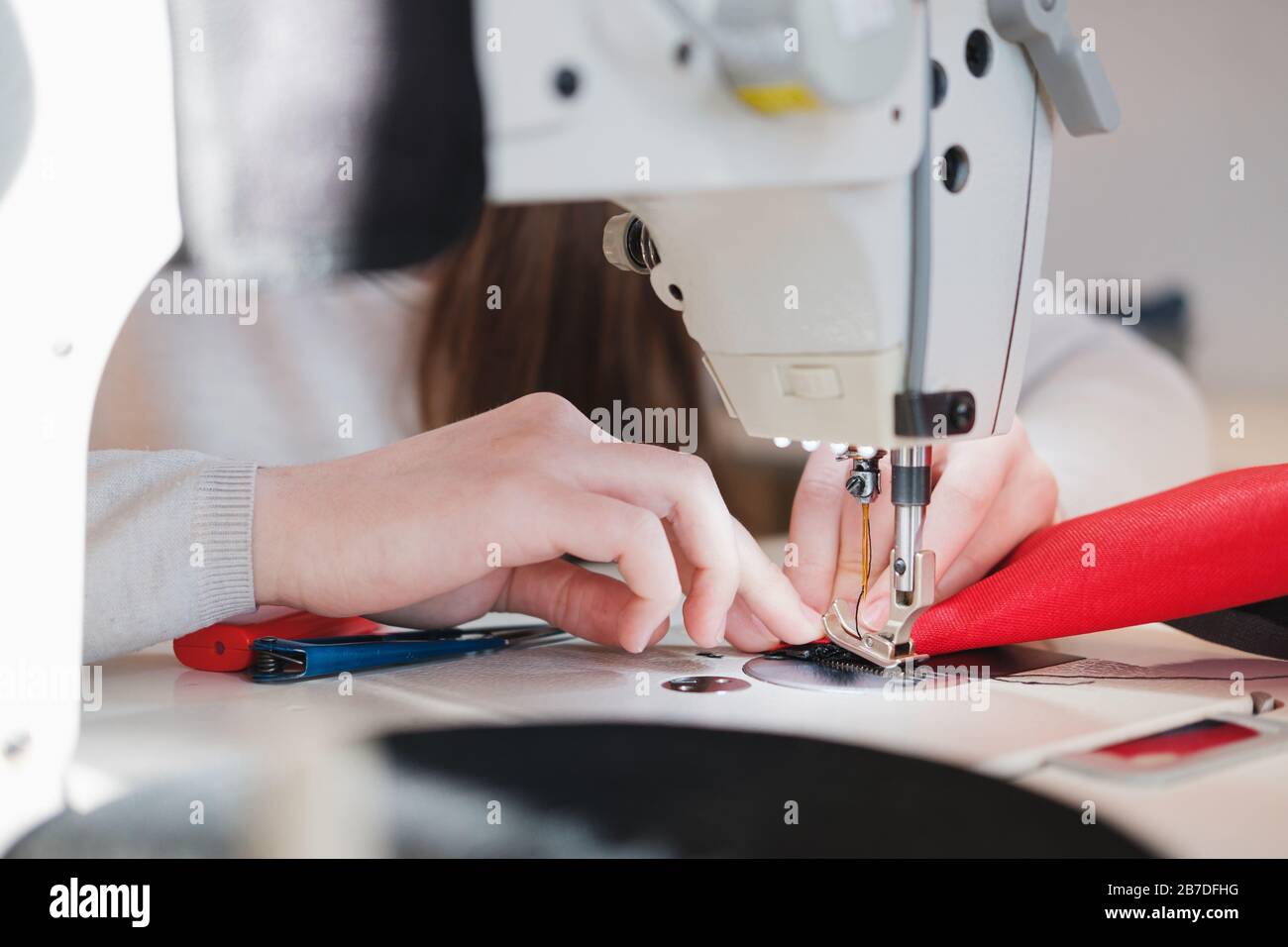 Seamstress hands doing precise work. Needlewoman at overlock sewing
