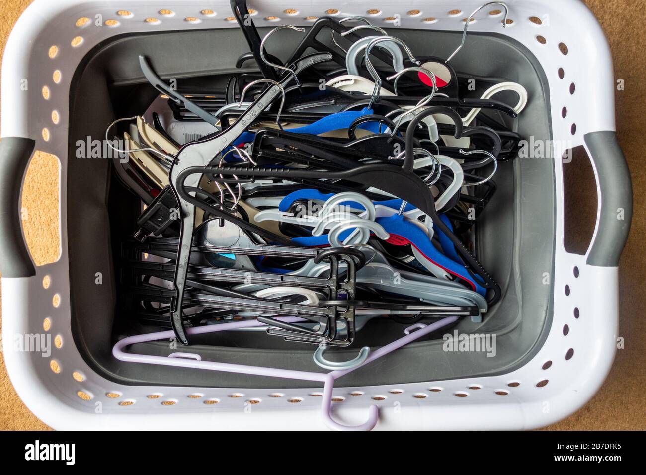 Looking down at a laundry basket full of plastic coat hangers. Stock Photo