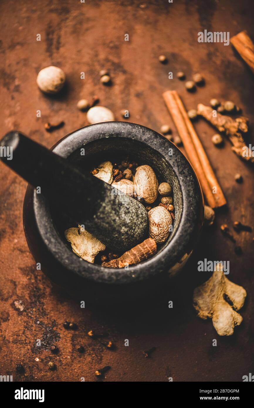 Turkish traditional seven spice Yedi Bahar mix for cooking. Black pepper, ginger, cloves, nutmeg, cinnamon, allspice and alpinia root in black plate o Stock Photo