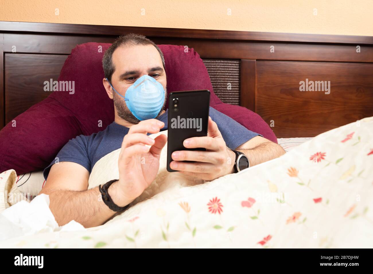 sick man laying in bed using smarthphone Stock Photo