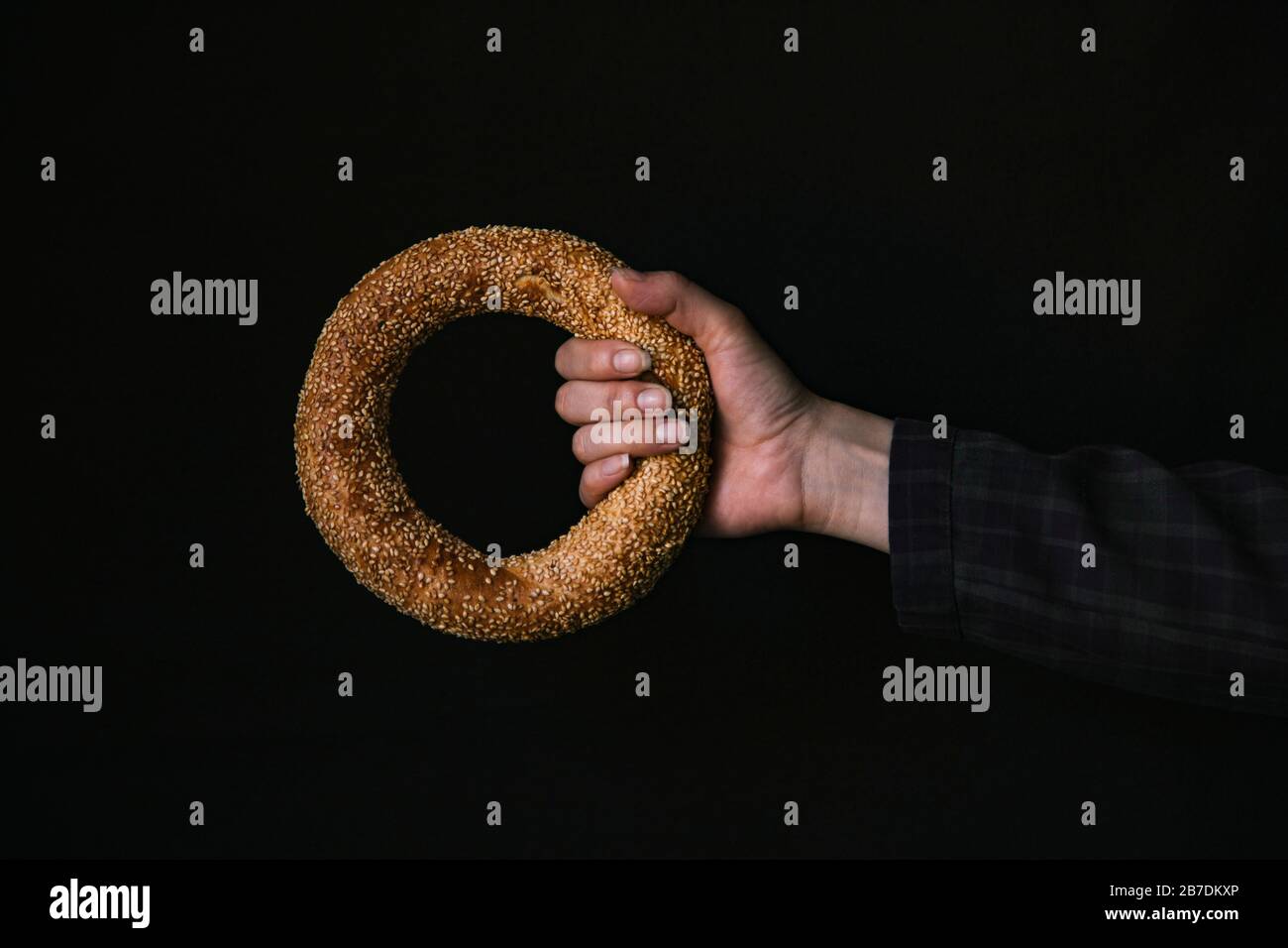 A Hand with a Bagel on a Black Background Stock Photo