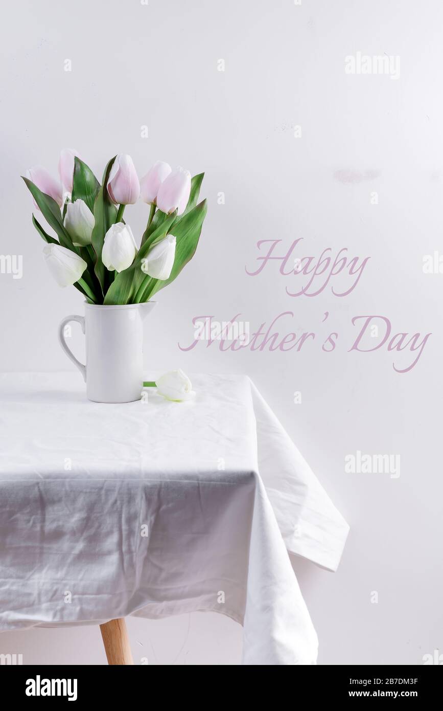 Bunch ofwhite and pink tulips in a white vase on white table with Mother's day lettering Stock Photo