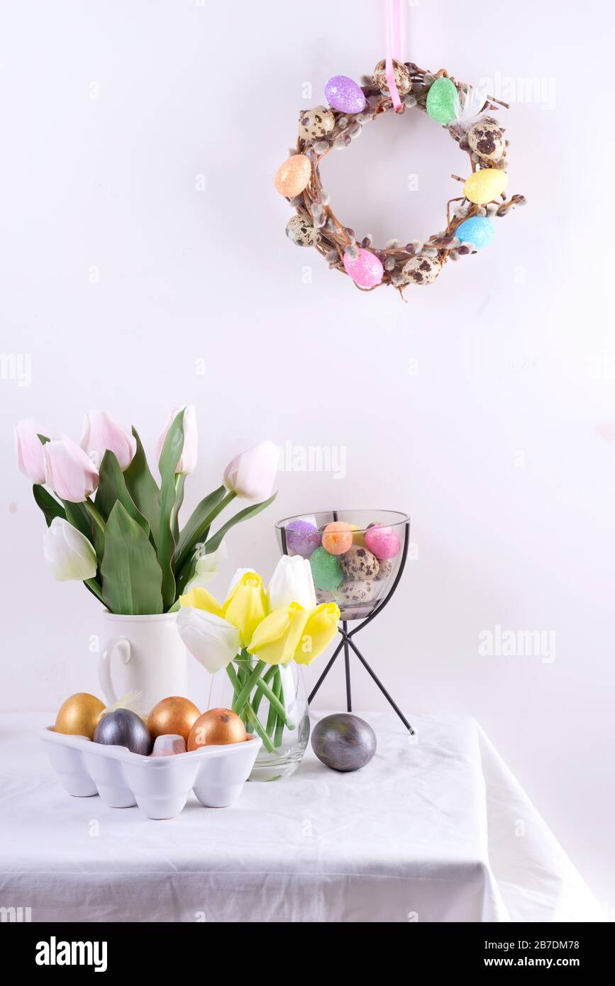 Easter table setting with tulips, easter eggs, cookies and wreath on white table Stock Photo