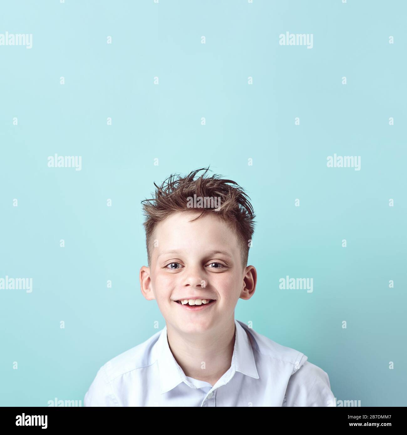 cheerful boy stands and smiles in a light shirt on a bright colored ...