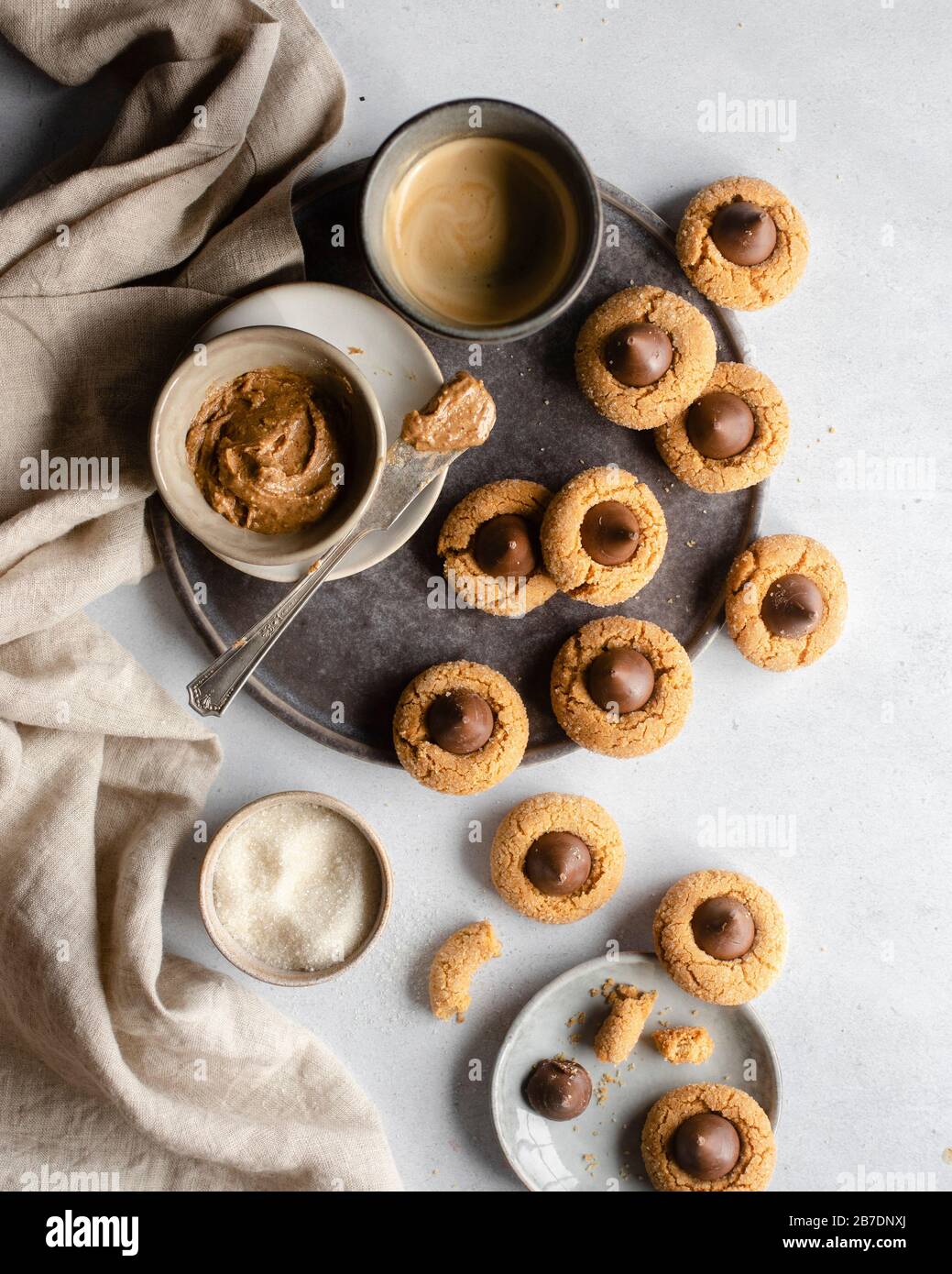 Peanut butter in a pinch bowl on a dark grey plate surrounded by chocolate kisses cookies Stock Photo