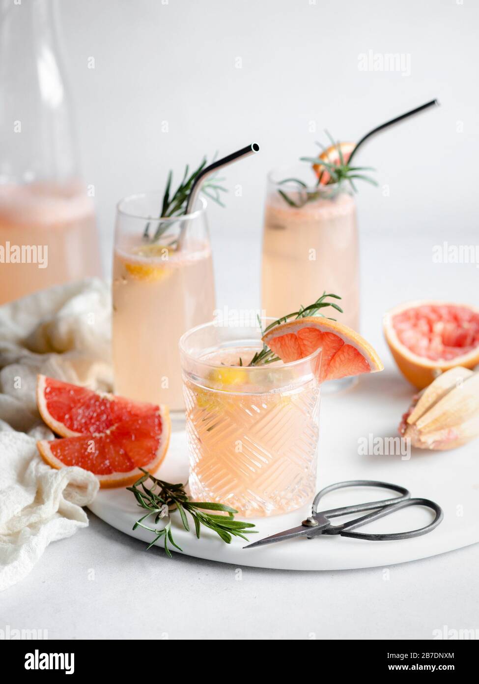 3 glasses of grapefruit cocktail on a marble tray with rosemary and grapefruit slices Stock Photo