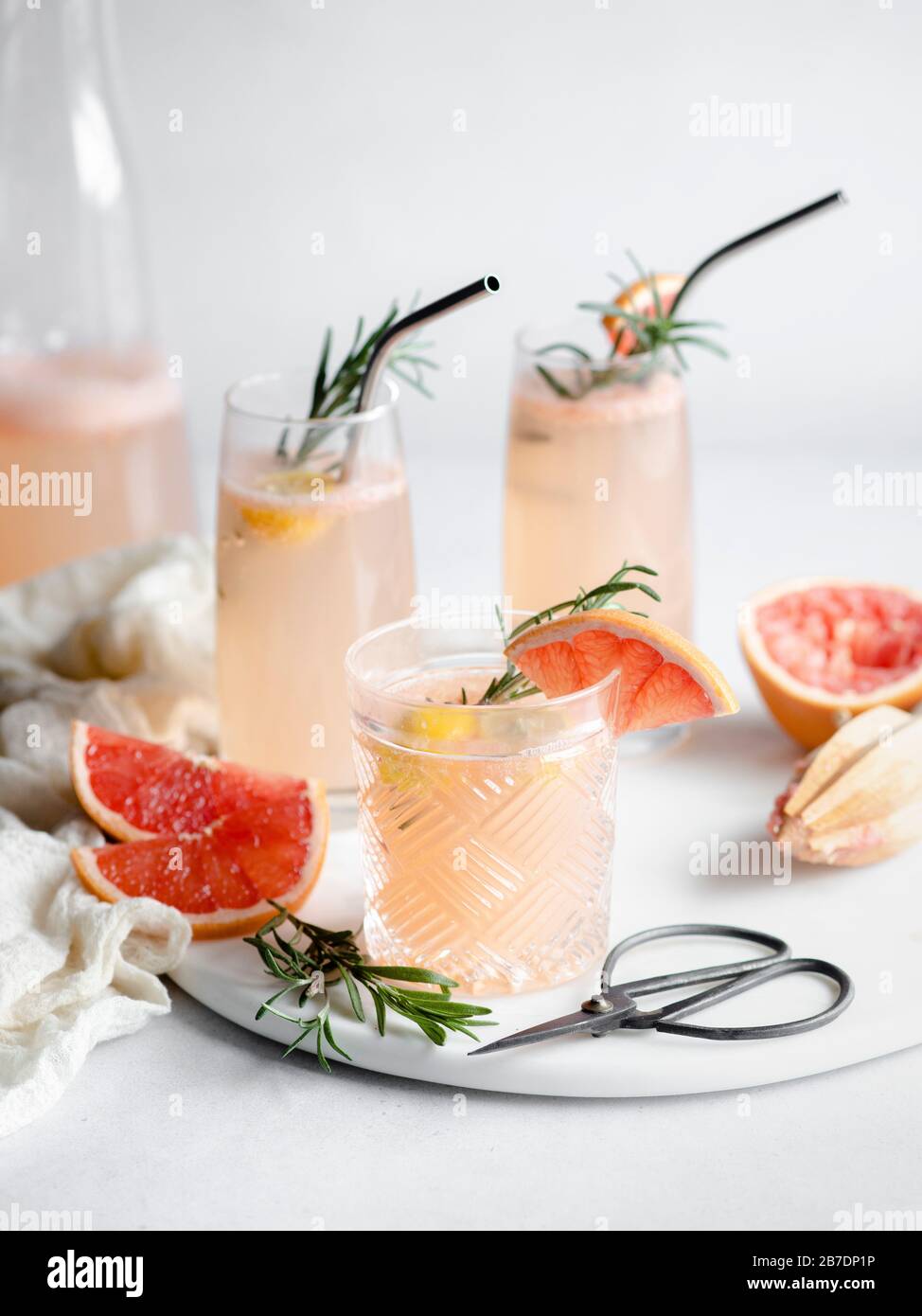 3 glasses of grapefruit cocktail on a marble tray with rosemary and grapefruit slices Stock Photo