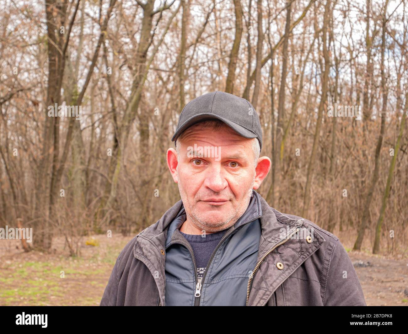 Facial expression of a mature man in a baseball cap with gray hair