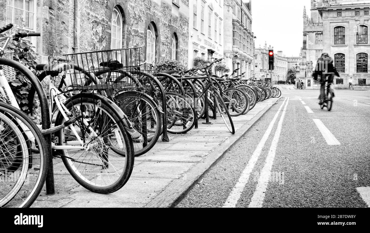 A black & white image of row Push Bikes parked up on busy Oxford Street, Oxfordshire,  England, UK, Britain Stock Photo