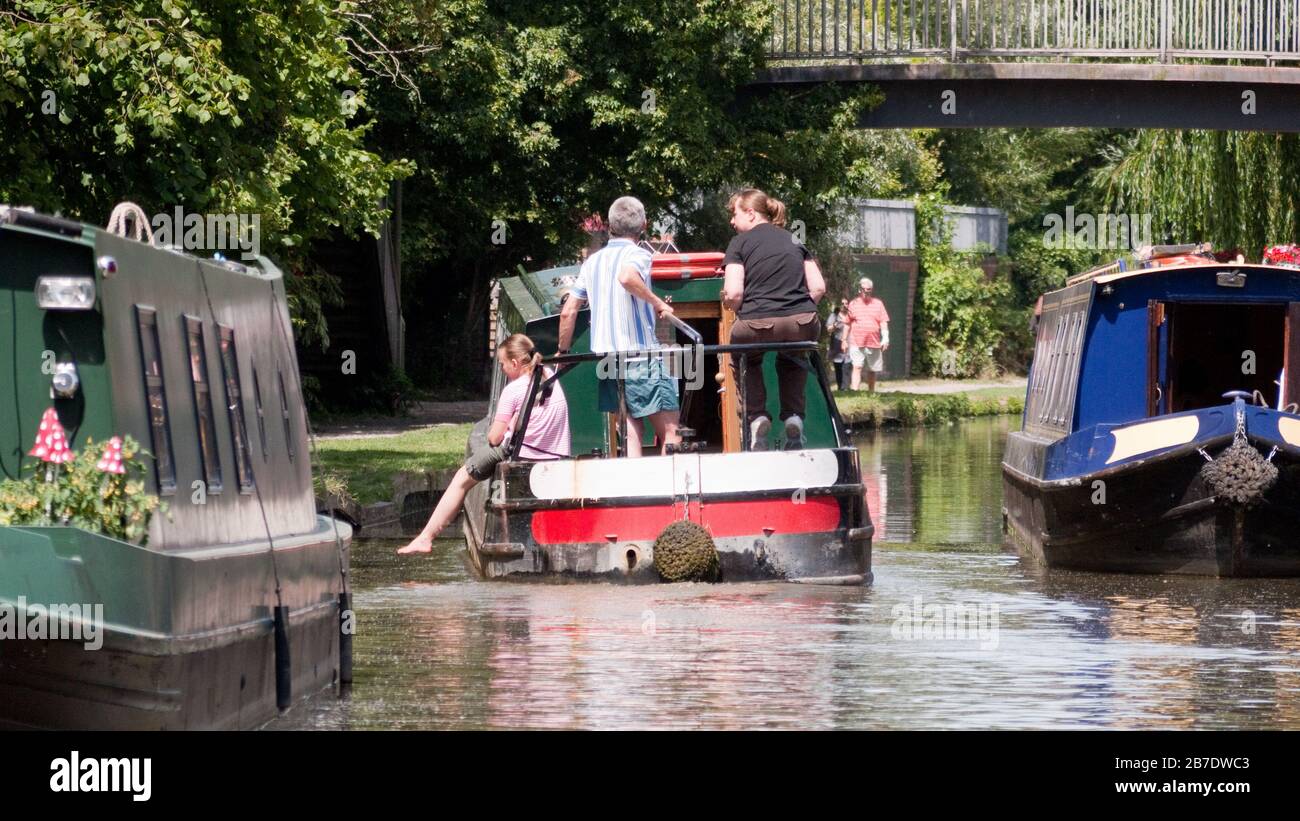 Hire boat on the Oxford Canal near Oxford with child dangling feet overboard while passing moored boats, Oxford Canal (South),  England, UK, Britain Stock Photo