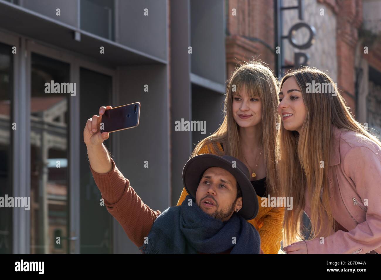 Latin American young man in a wheelchair taking a selfie with a mobile together with two young Caucasian girls Stock Photo